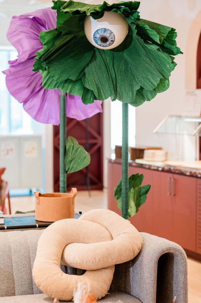 Purple and green giant surreal flowers with eyeballs and a corporate party 