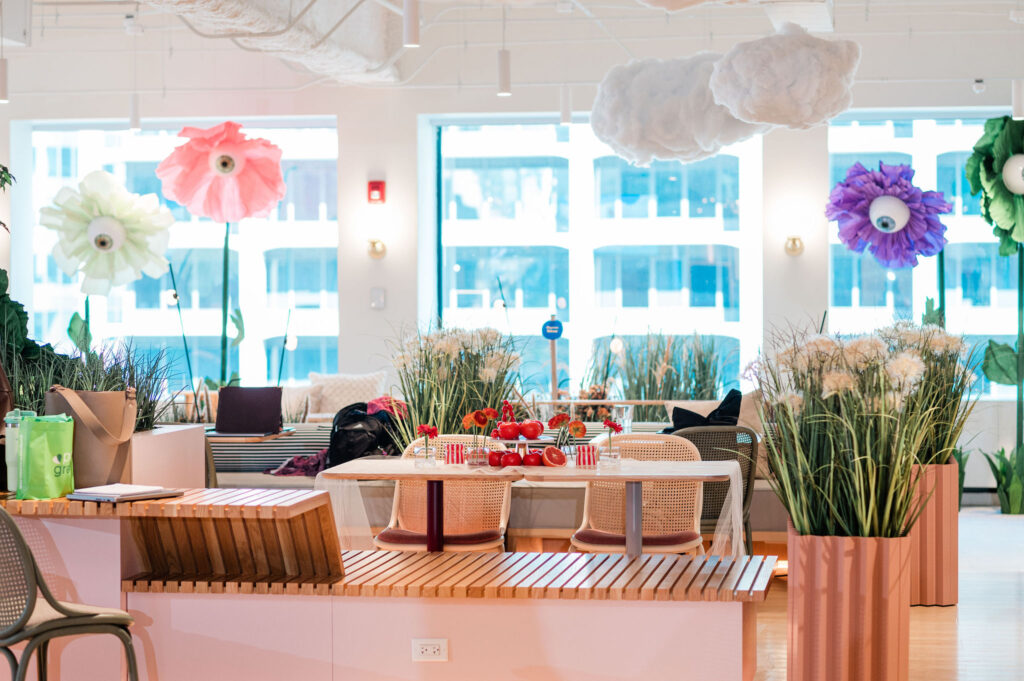 Surreal event entrance with oversized fantasy flowers and whimsical summer party decor at a corporate Dreamland themed garden party.