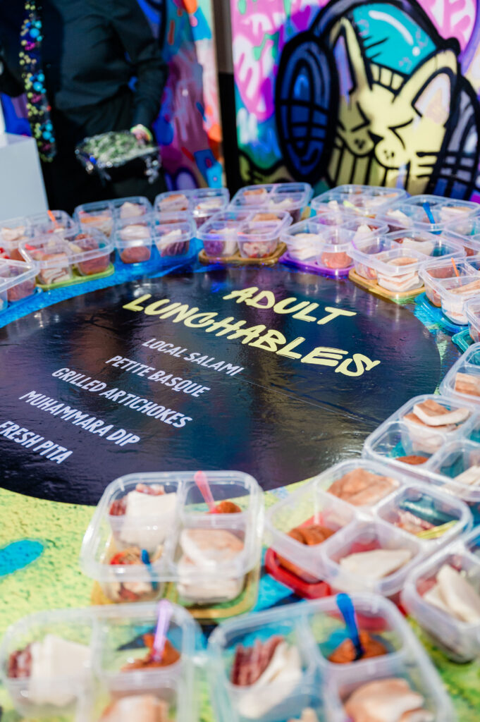 A table with a sign that says adult lunchables with containors filled with food