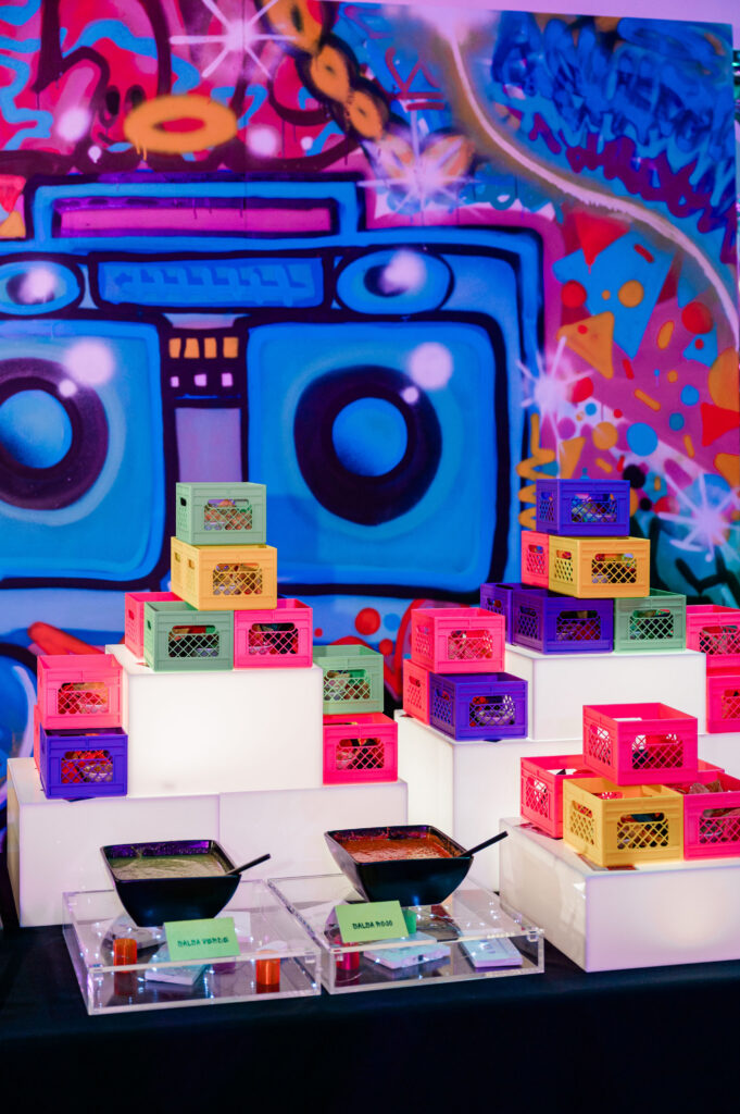 A food display of bright colored mini 3d printed crates holding chips and guac