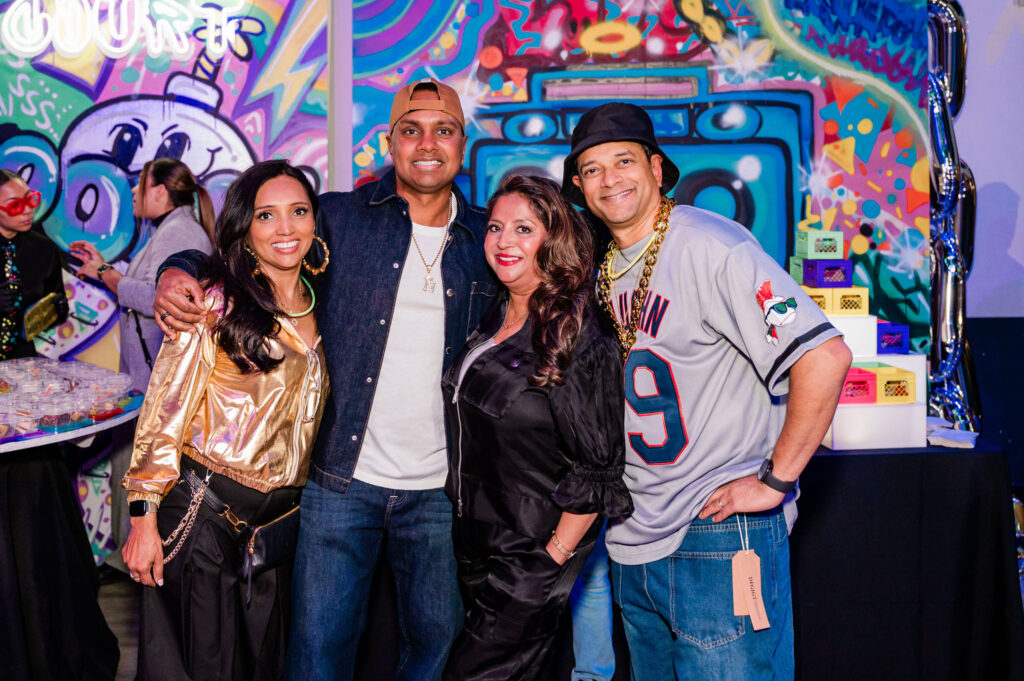 A group of people standing up against a custom graffiti backdrop 