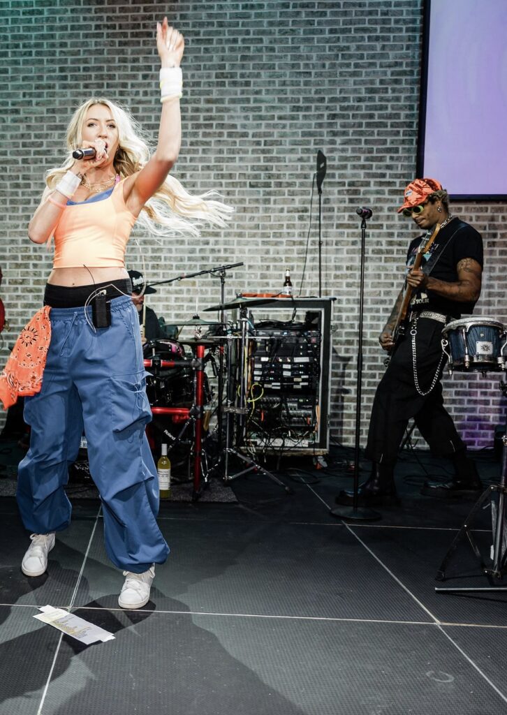 a lady jumping in the air on a stage singing 