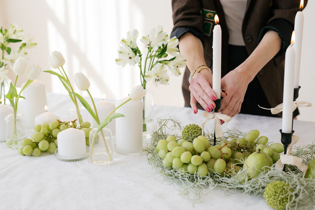 A womens hands adjusting a candle stick on a  lace themed tablescape with black and white candlesticks