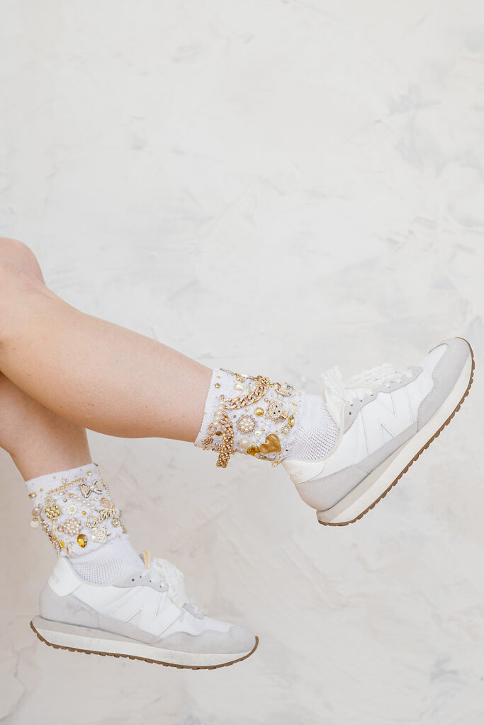 a womens legs in the air with brooched socks and white tennis shoes