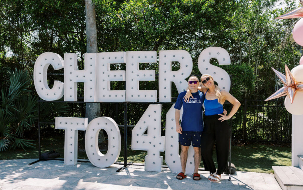 Large light up letters : CHEERS TO 40 with the birthday couple hugging in front of it. 
