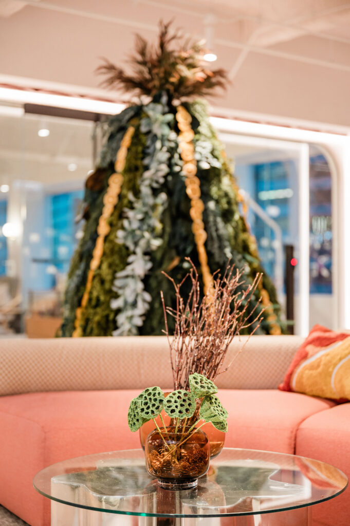 A heavily decorated evergreen tree. The tree is adorned with lots of different greenery and dried oranges. 