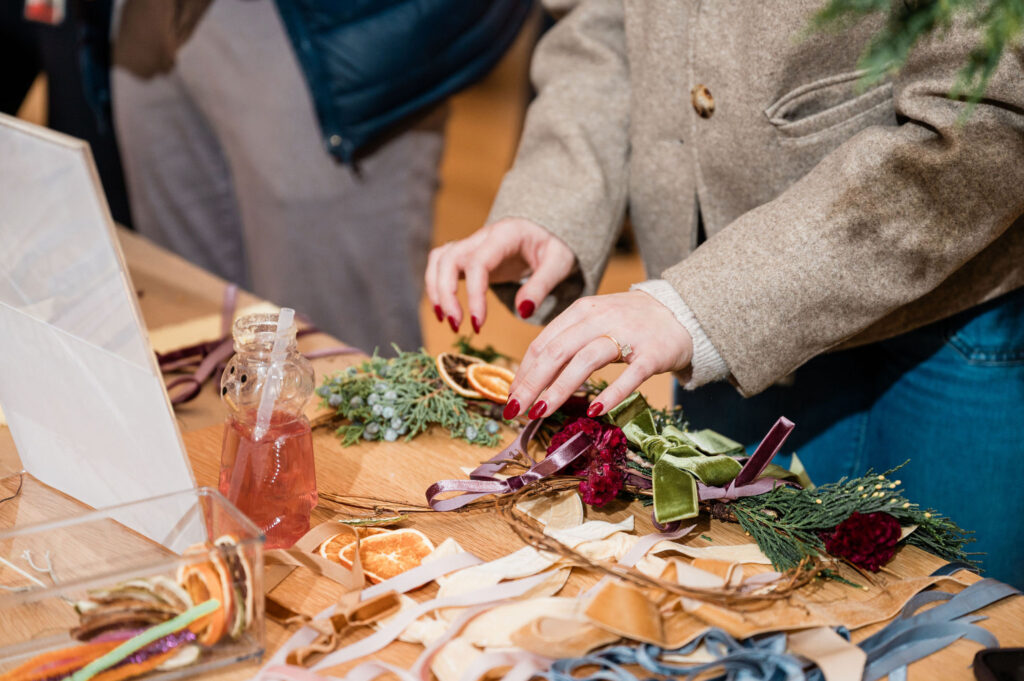 A person making a dried floral wreath at a wooden table