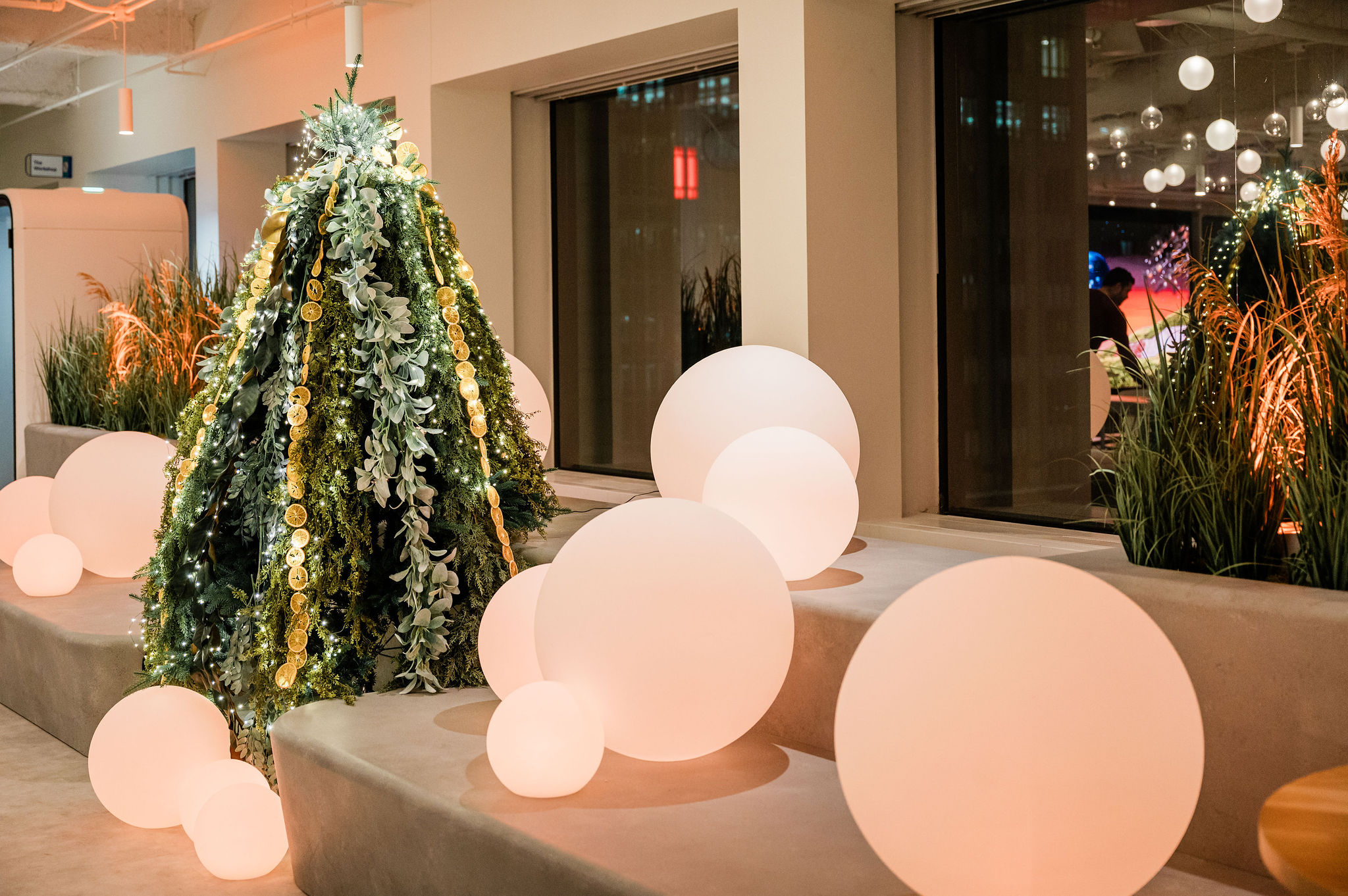 layered greenery holiday tree with large white orbs surrounding the tree