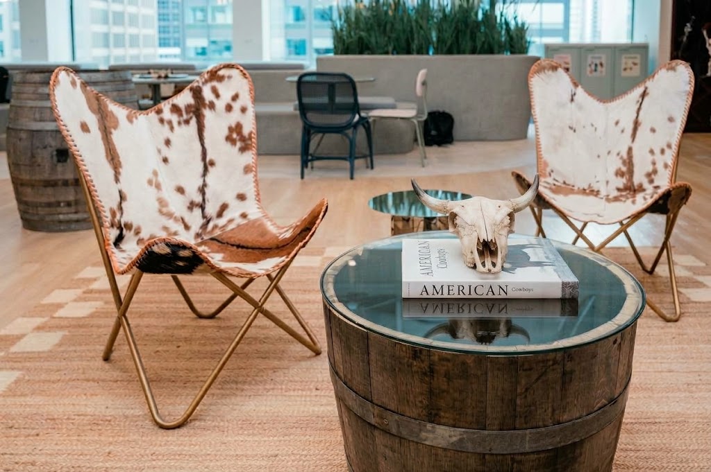 cow hide lounge chairs and a barrel side table at a corporate office party